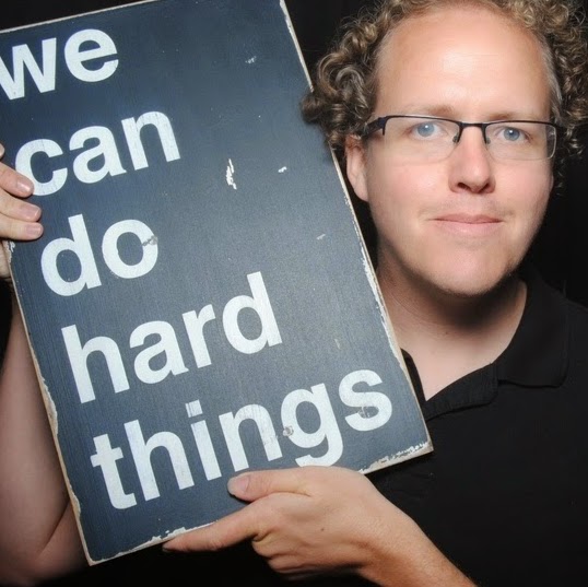 A man holding a sign that reads &ldquo;we can do hard things.&rdquo;